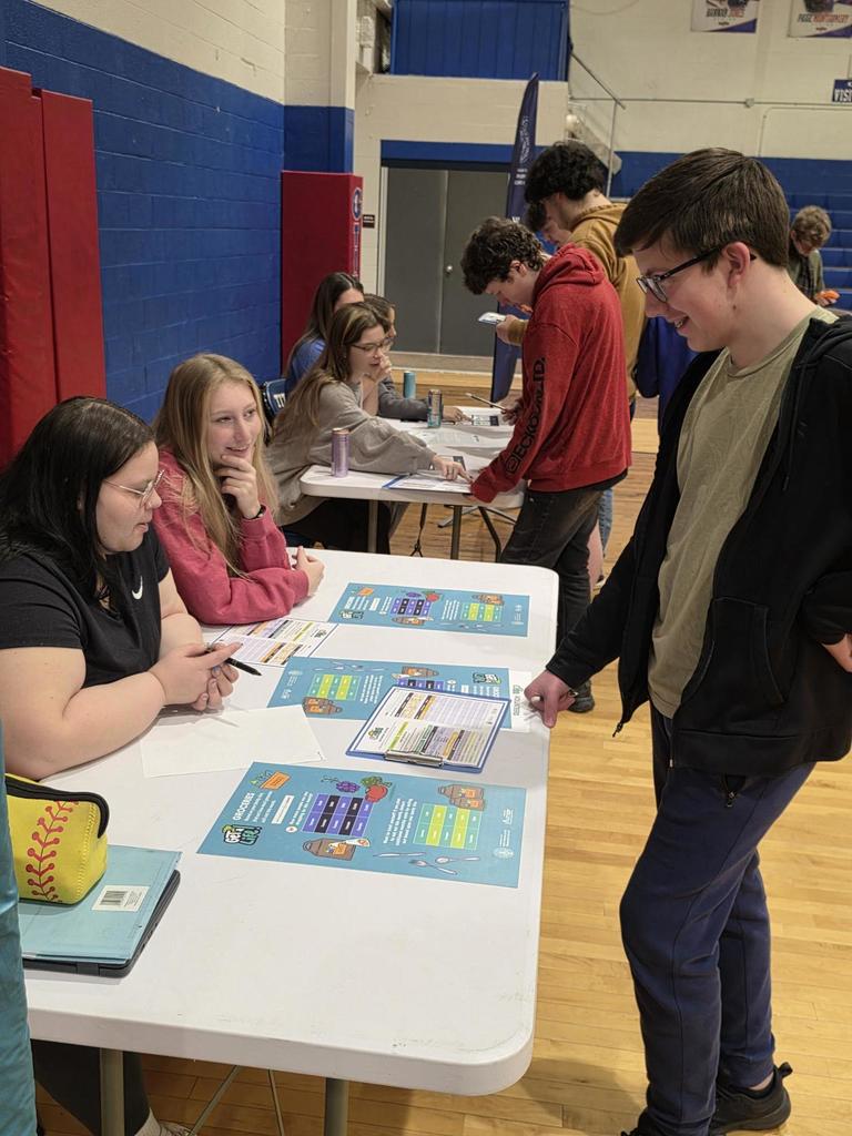 students at a table talking to volunteers