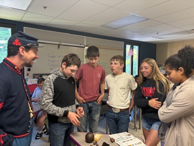 a gbroup of students and mr. barker doing a hands-on activity with civil war items