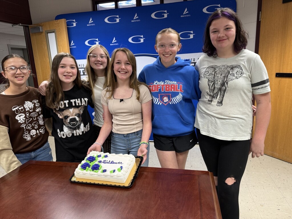 students in front of a cake that says "girl power"