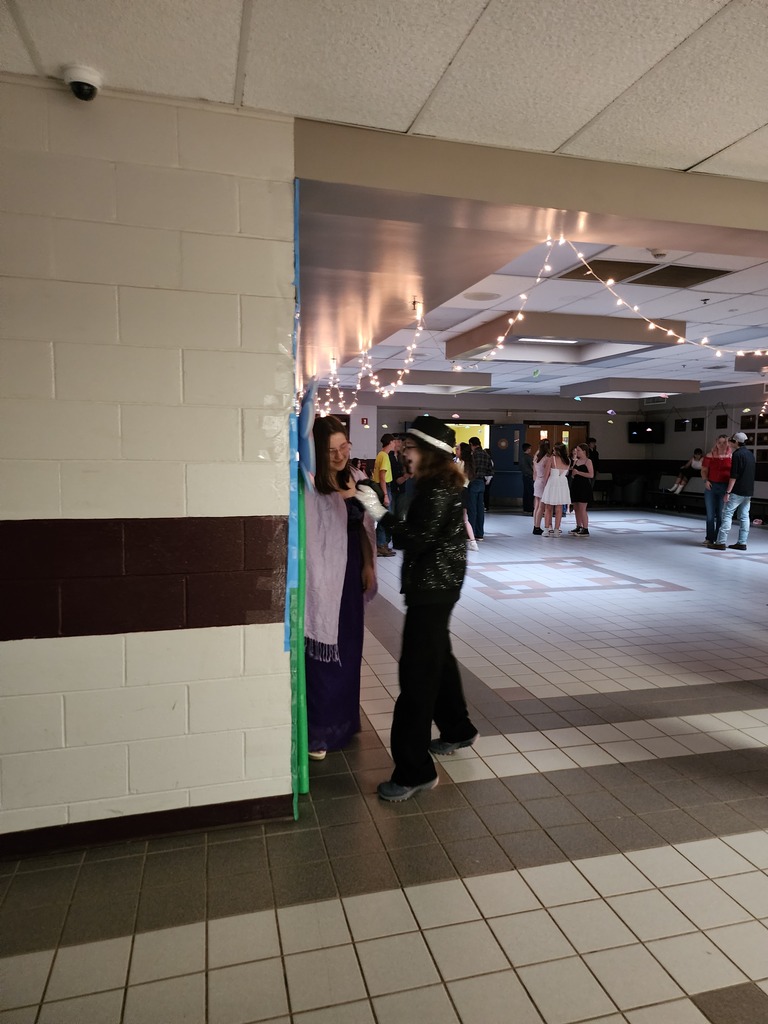 two students taking pictures at the backdrop
