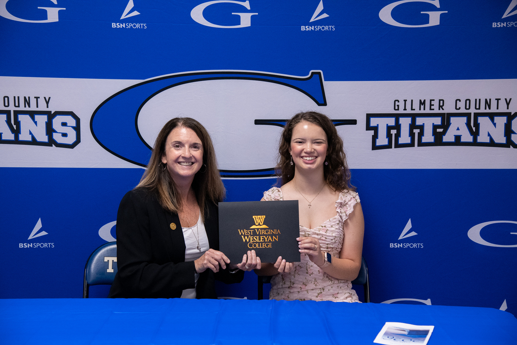 Jenna Smith with WVWC rep holding up a certificate in front of the titans banner 