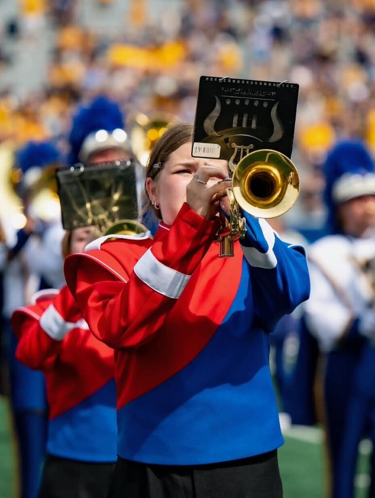 student on the field for WVU band day playing the trumpet