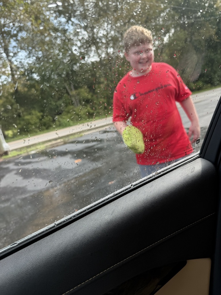 a student cleaning a car, photo shot from inside the car
