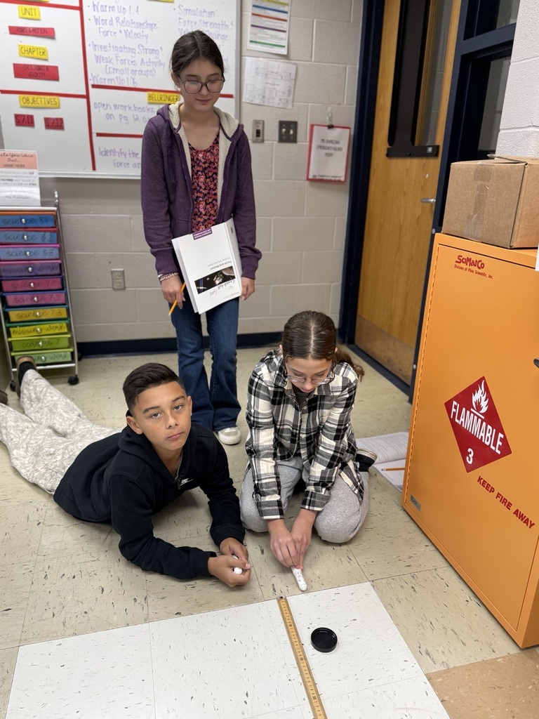 students with two air hockey pucks about to measure distance traveled