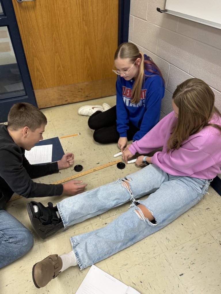 students with two air hockey pucks about to measure distance traveled