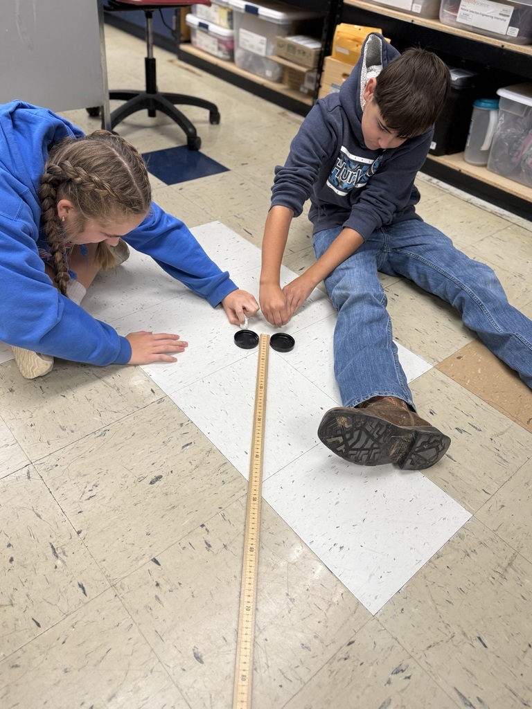 students with two air hockey pucks about to measure distance traveled