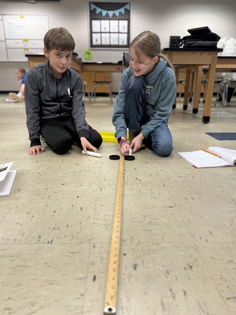 students with two air hockey pucks about to measure distance traveled