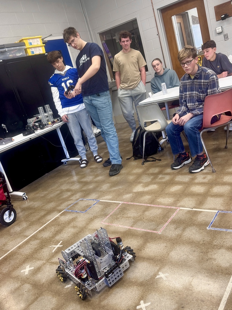 Students gather around a student driving a robot.