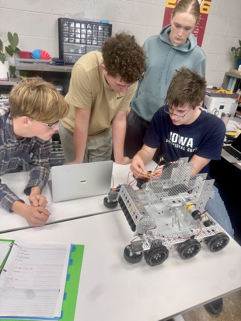 Students gather around a student wiring a robot.