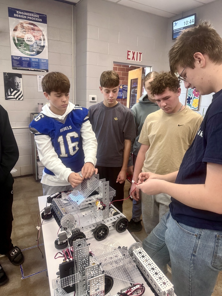 Students gather around a student wiring a robot.