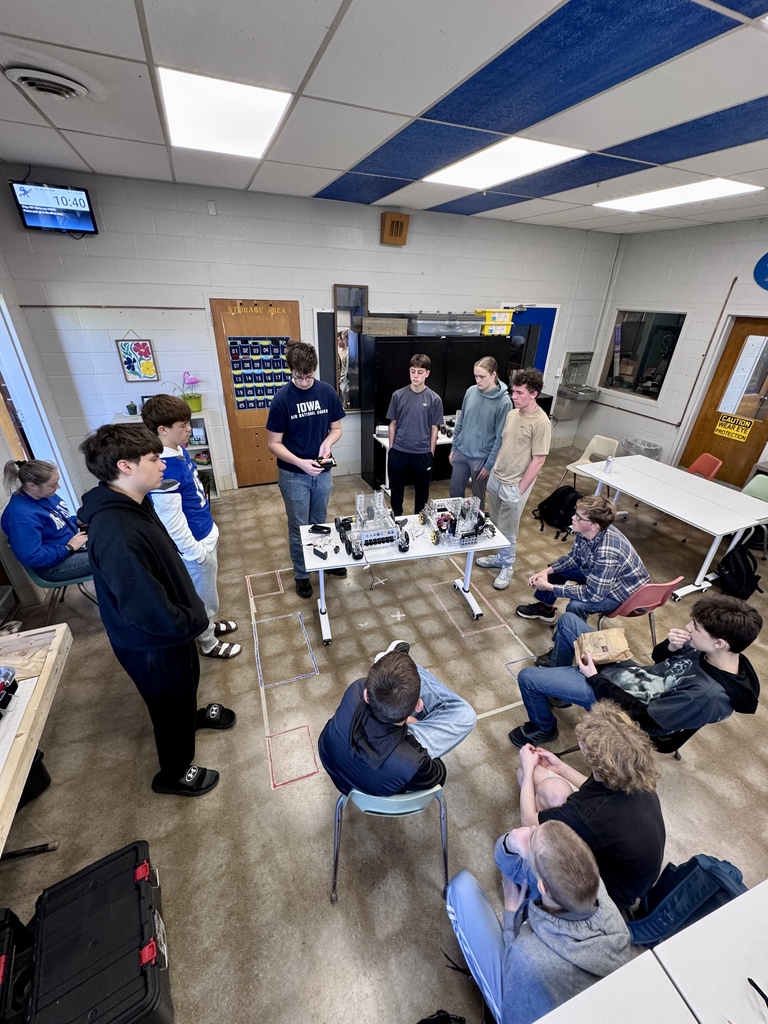 Students gather around a student wiring a robot.
