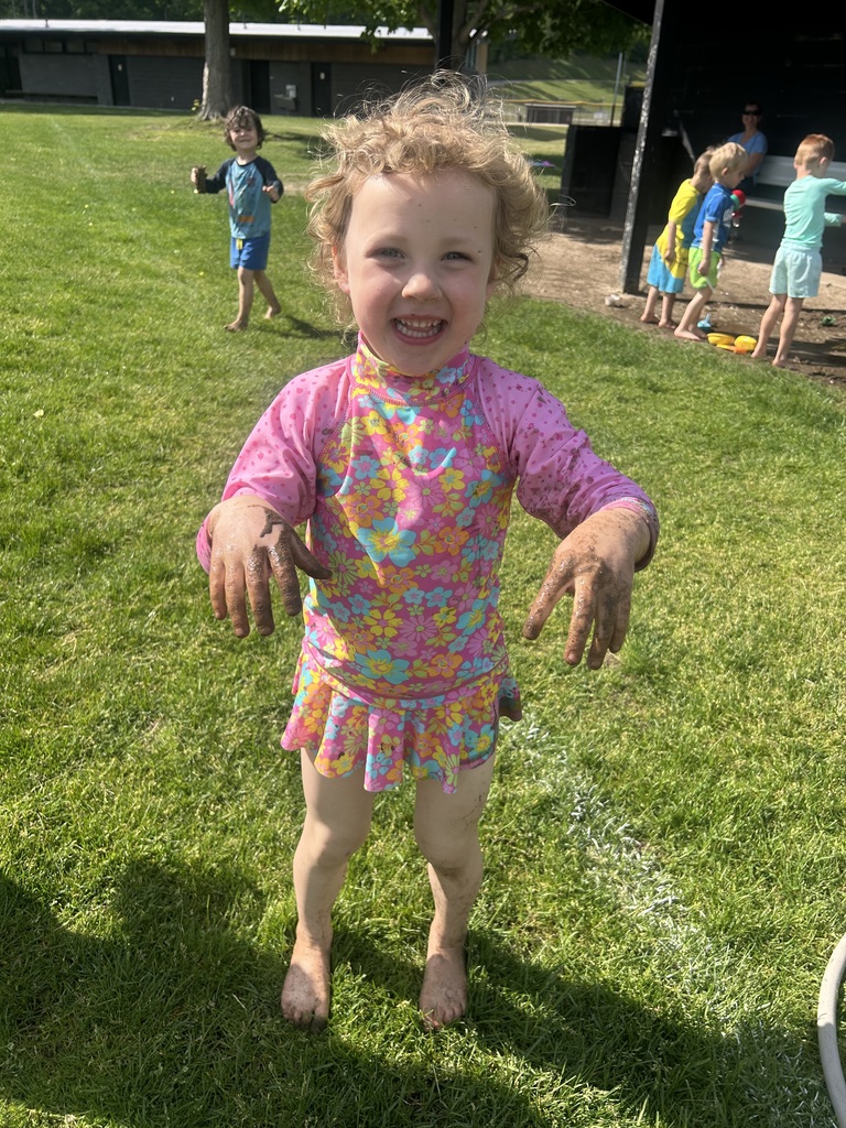 A preschooler is having a blast in the mud