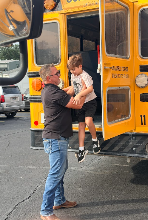 Mr. Bachman helps student off of bus