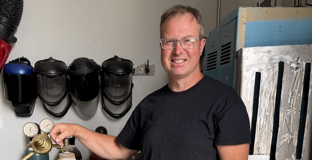 Mr. Del Medenbach in the Glenwood Shop next to some welding equipment.