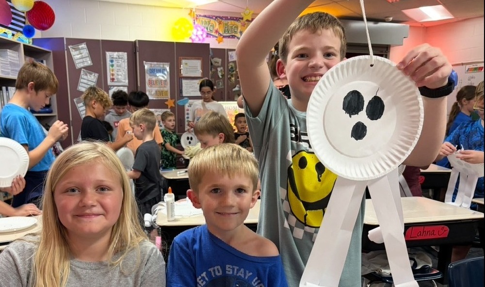 Students building a ghost together out of paper plates and paper