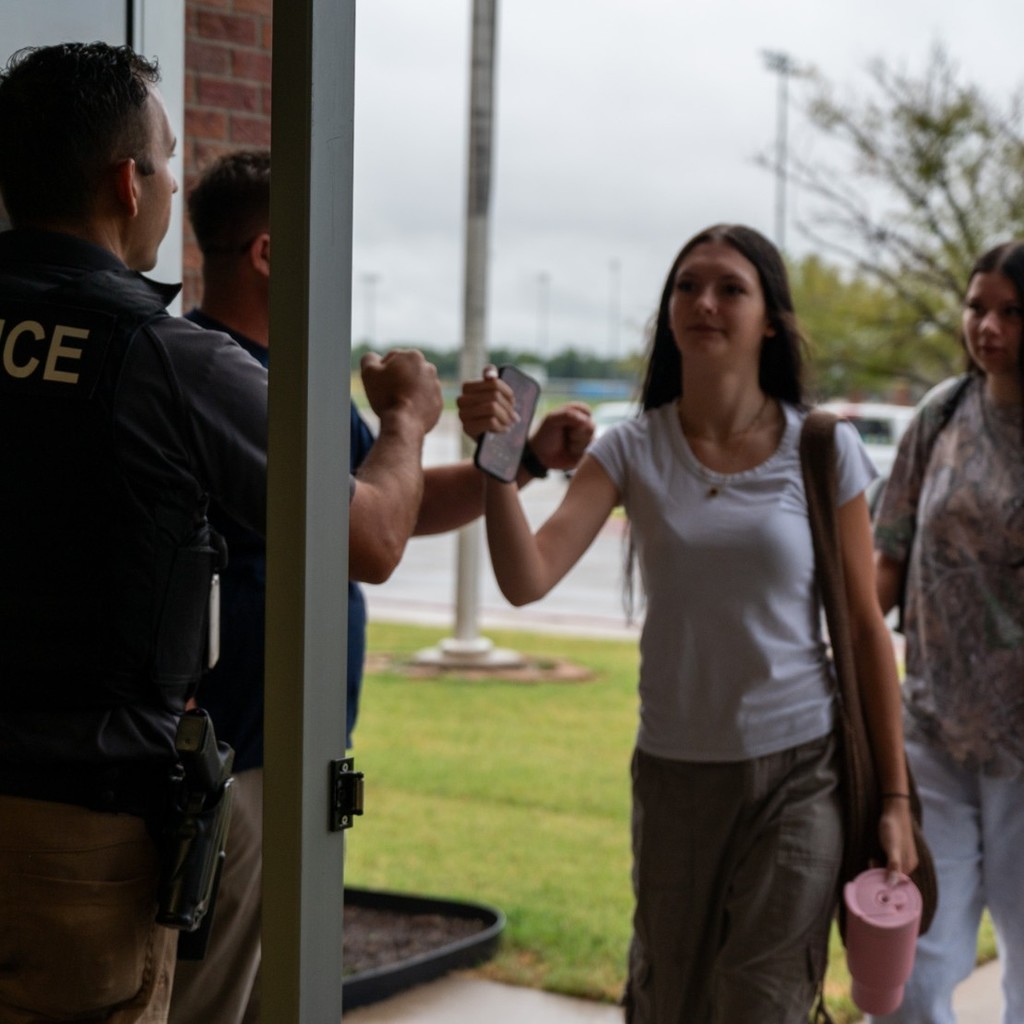 Walking in to building, students and staff give each other fist bumps.