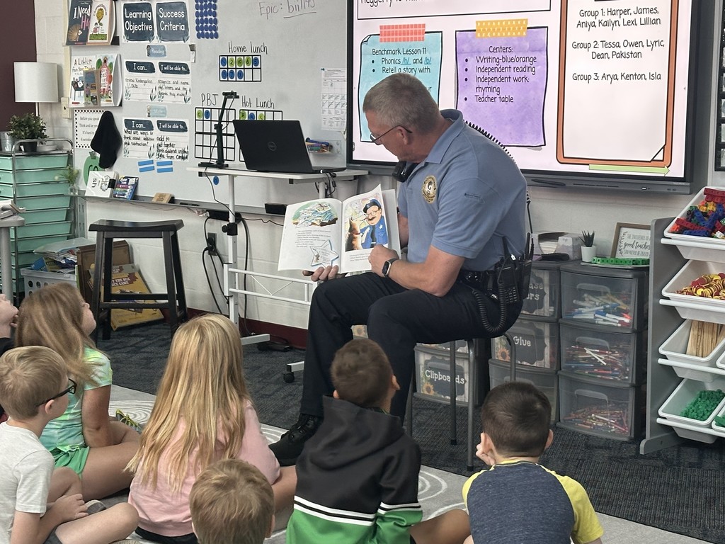Officer Camp reading a story to 1st graders