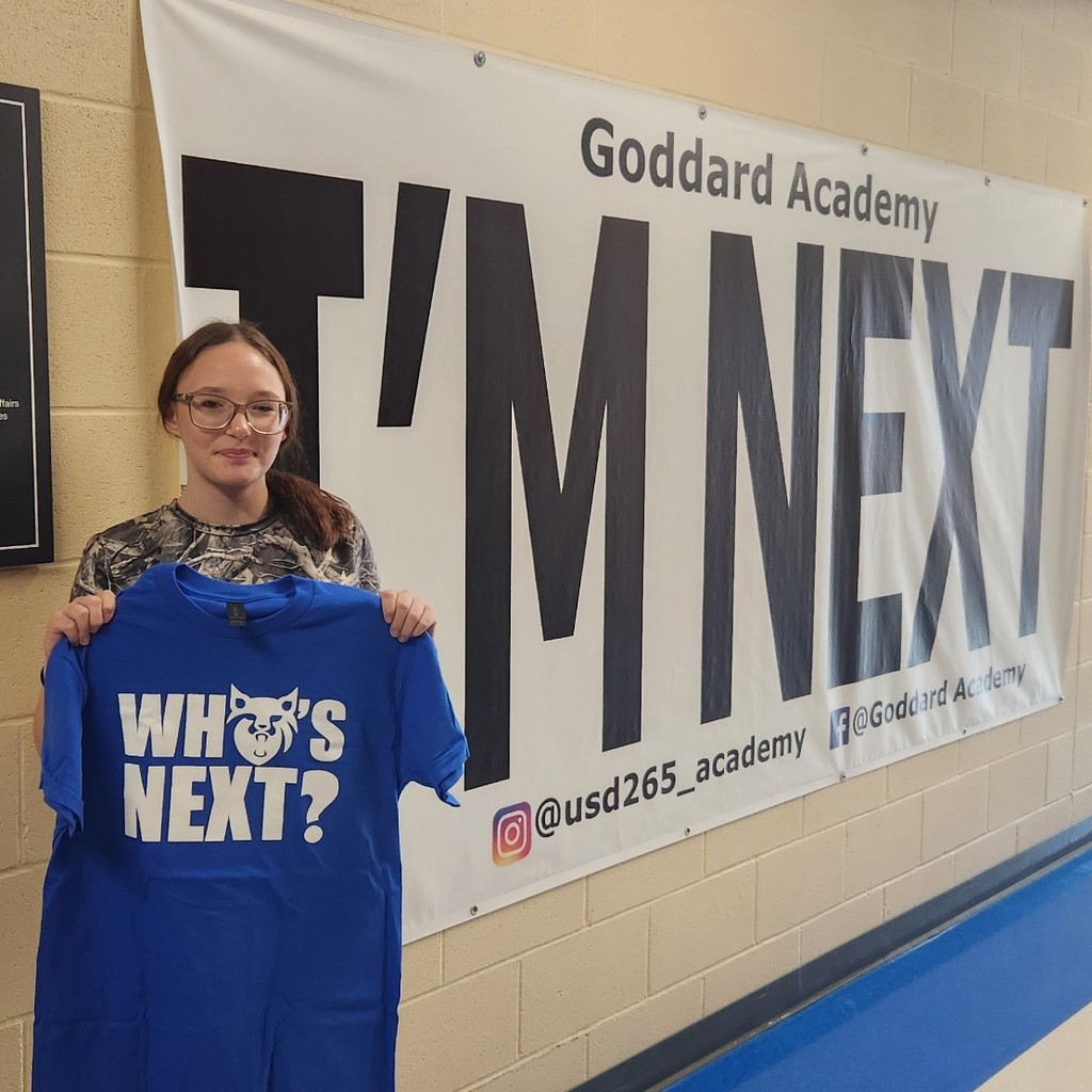 Holding "who's next" shirt in front of "I'm Next" banner