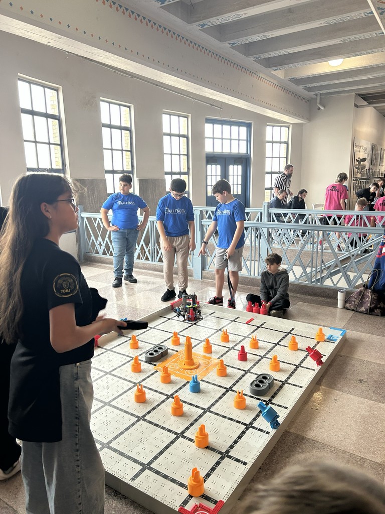Students gathered around the robotics challenge board on the floor.