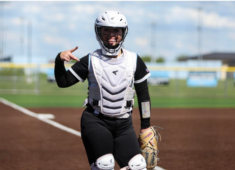 Background:  Softball field dirt, green grass, & blue skies; picture of EHS student athlete Elleigh Tarpley in a catchers uniform