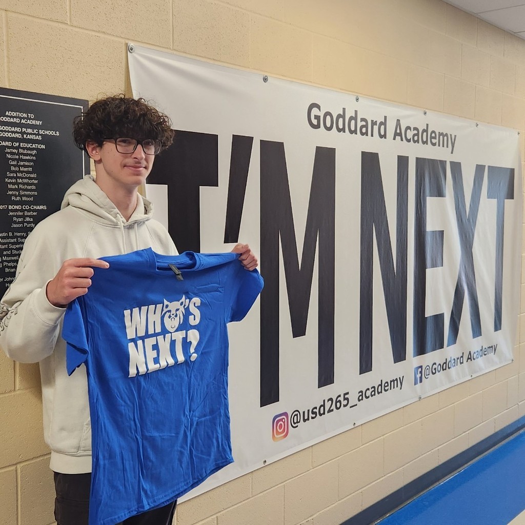 With "Who's Next" shirt in front of "I'm next" banner