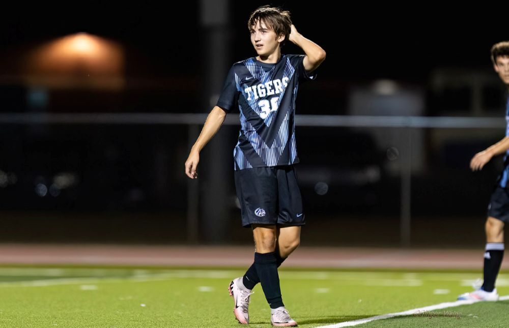 background:  black, green soccer field, EHS Soccer player Jackson McCoy, with blue & black striped uniform, black shorts, 