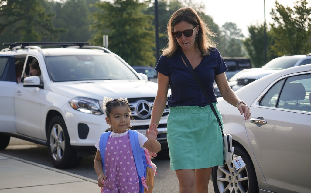 Principal walking with student from car rider line