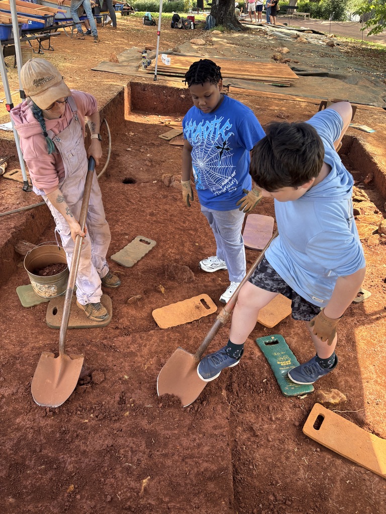 Students using shovels to dig at an archeological dig site