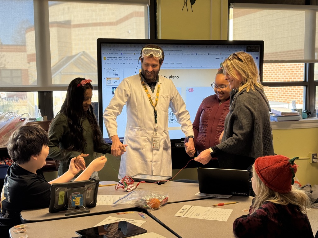 Mr. Mock, Mrs. Cosby, and students demonstrating how electricity can flow through people