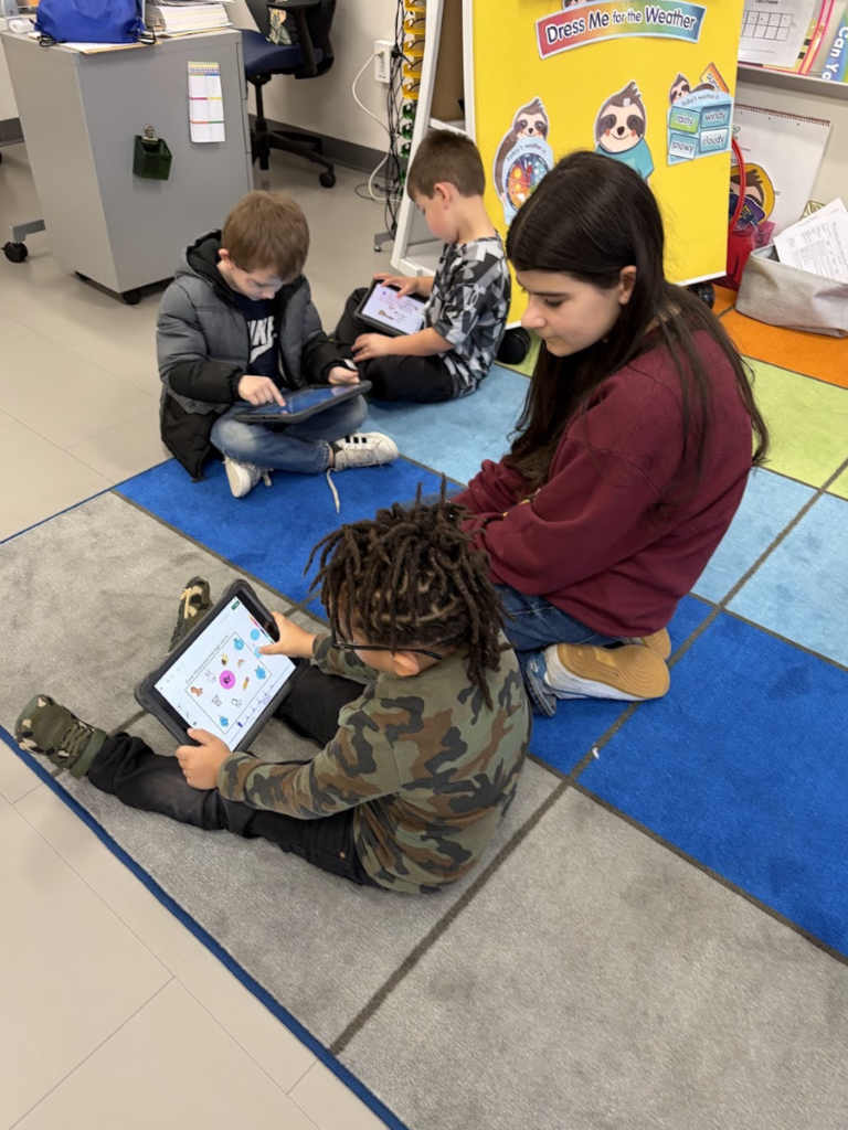 Girl helping elementary student with iPad