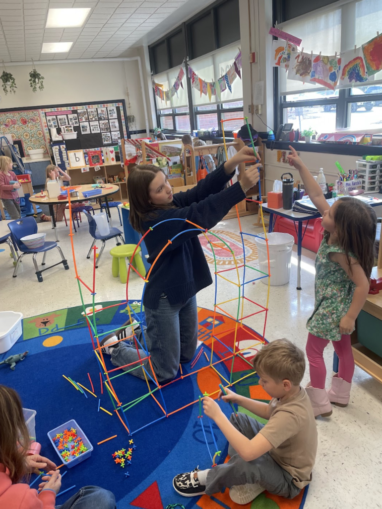 Girl building with elementary students