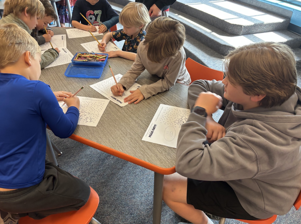 Boy helping elementary students with worksheet