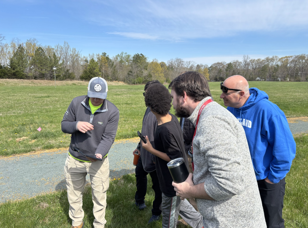 Drone operator showing students his ipad with drone software