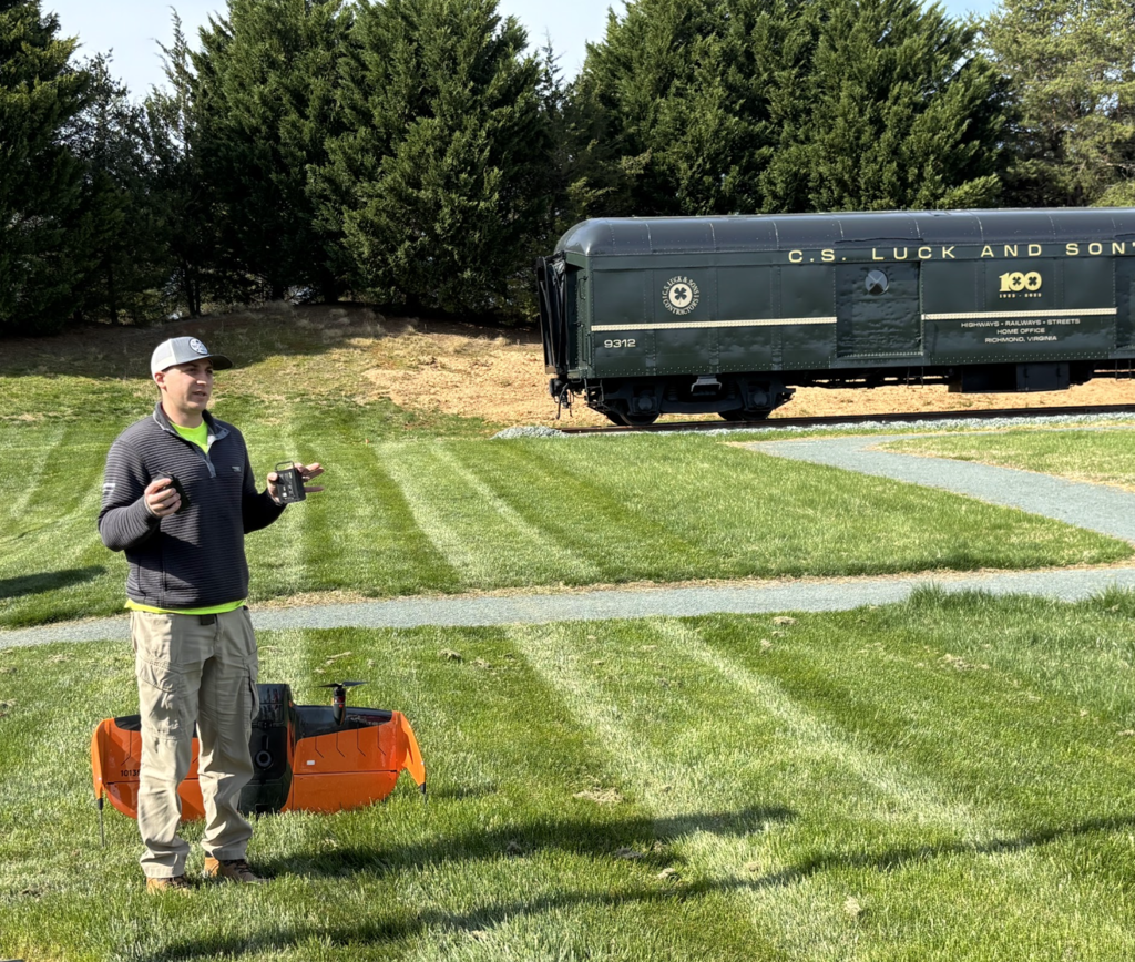 Drone operator standing in front of an orange drone