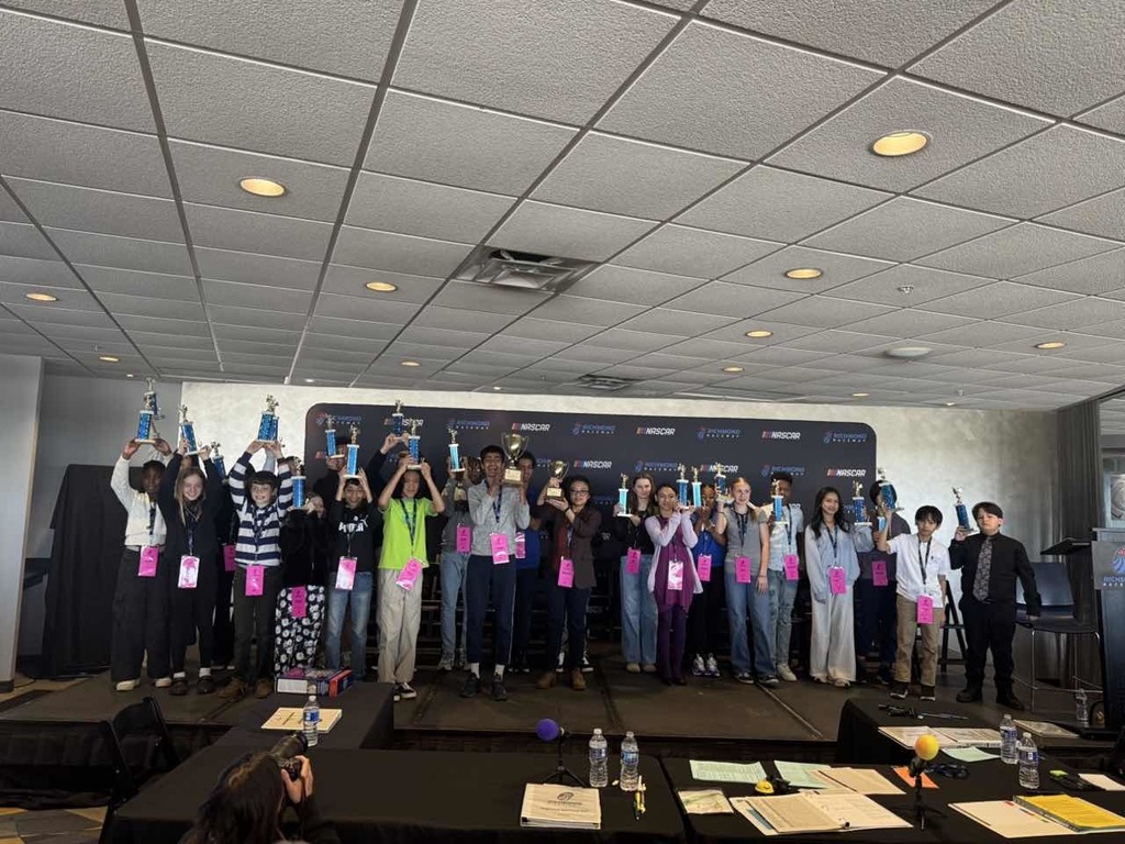 Spelling bee participants holding up trophies 