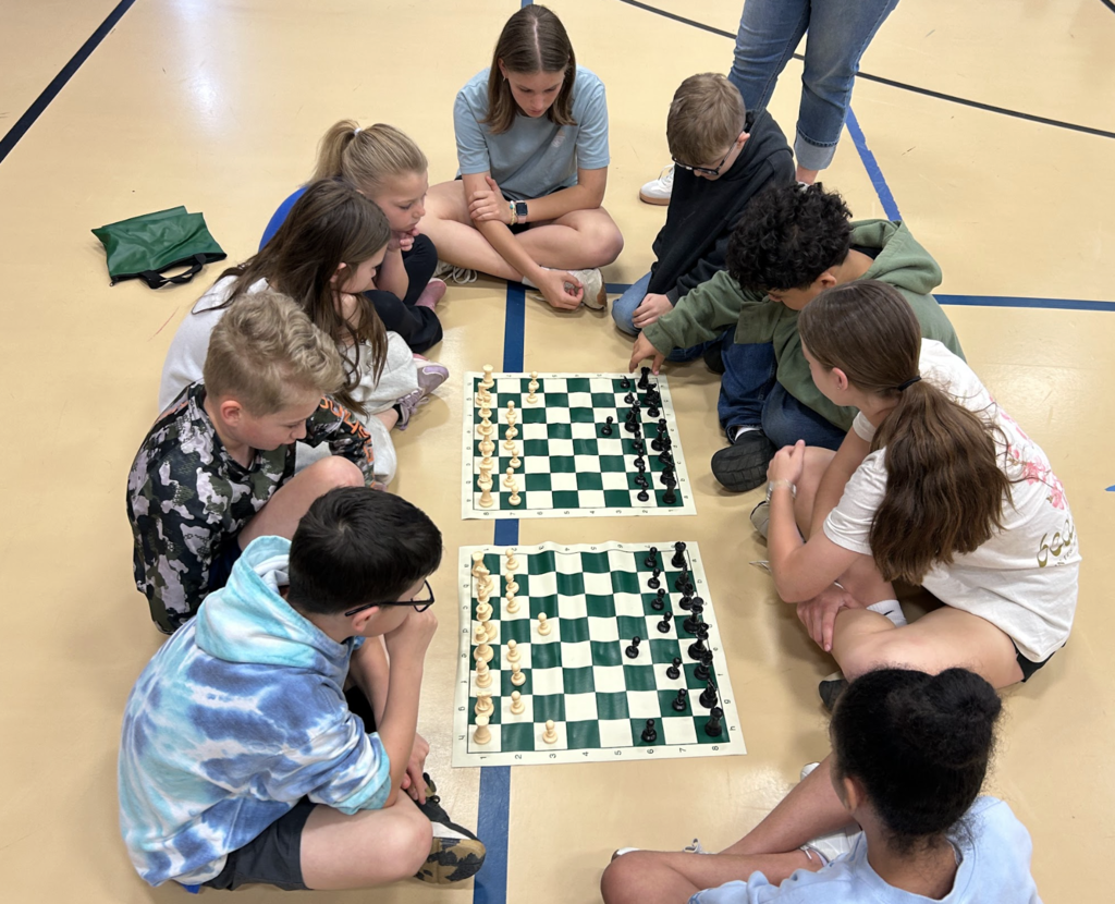 Students sitting around two chess boards