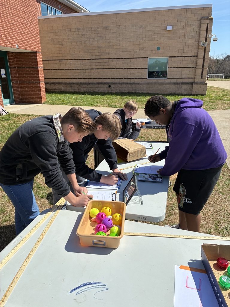 Students read science station instructions with bowl of whiffle balls