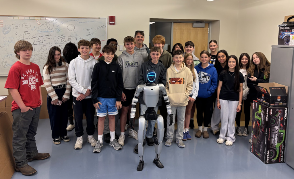 Group of students and Mr. Beasley standing with a humanoid robot in front