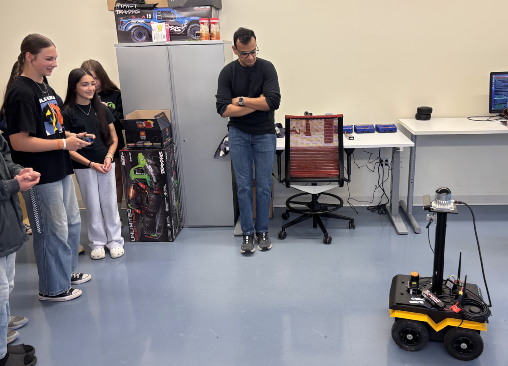 Female student driving a robot with professor looking on