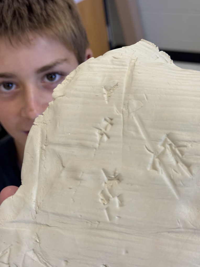 Student showing off writing on clay tablet