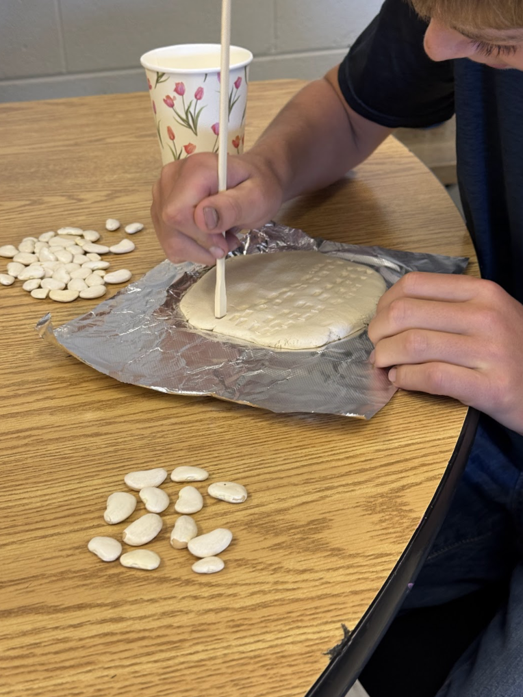 Student practicing writing on clay