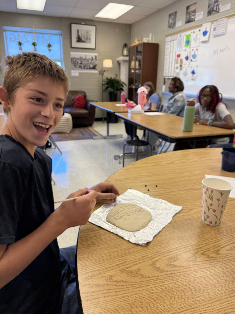 Student practicing writing on clay