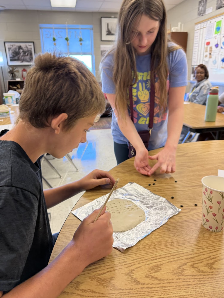 Students practicing writing on clay