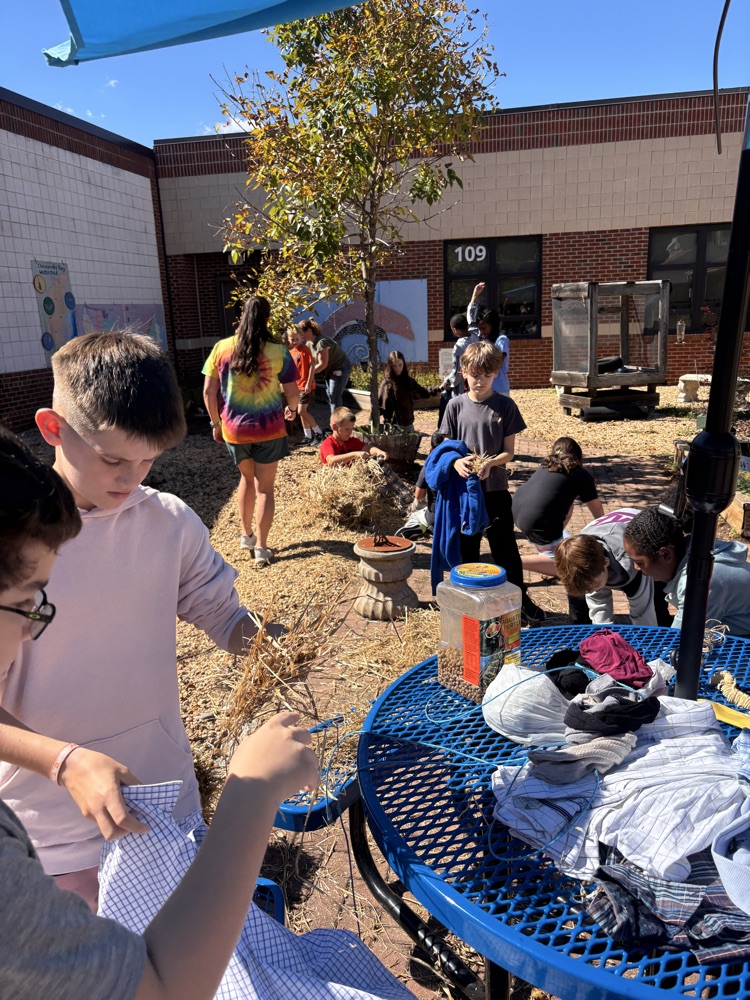two student stuffing the shirt of their scarecrow