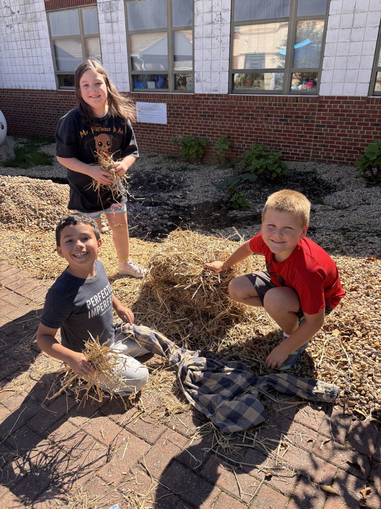 A group of students works together to stuff their scarecrow