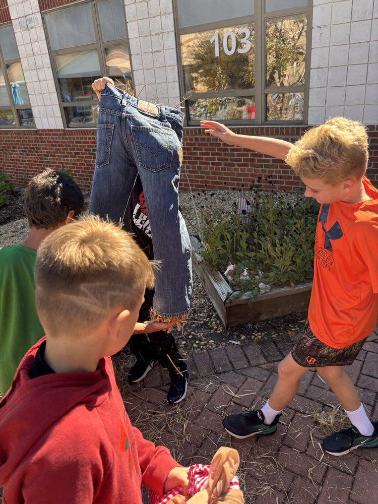 A group of students works together to stuff the pants of their scarecrow