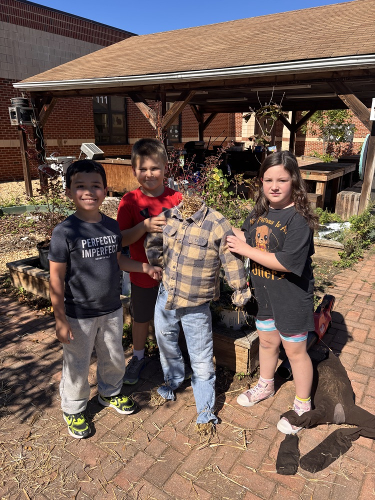 A group of students holds up their scarecrow