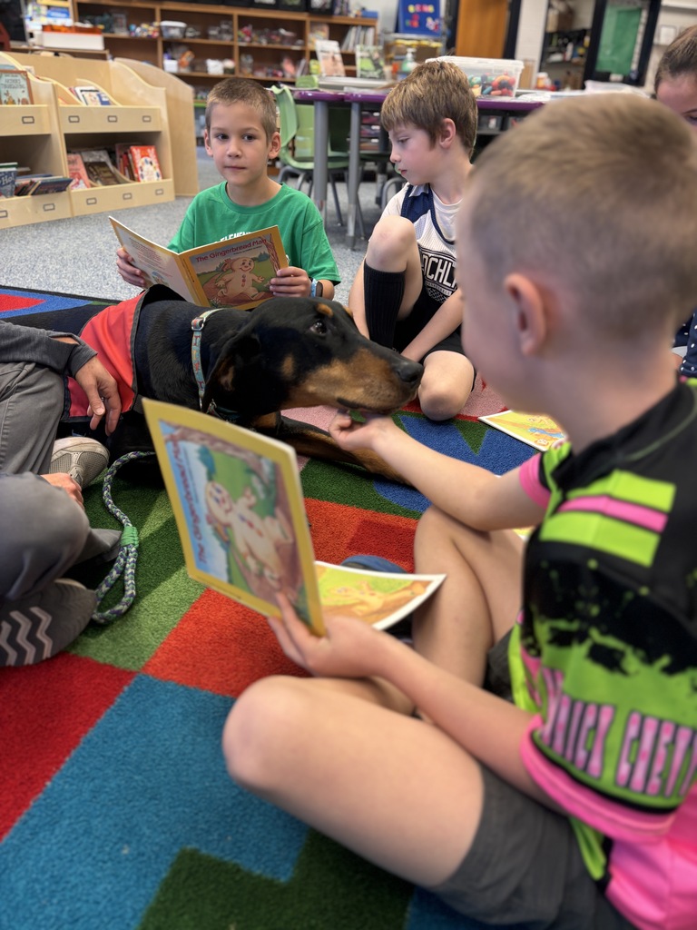 Students petting the Reading Therapy Dog, Pi, while they read