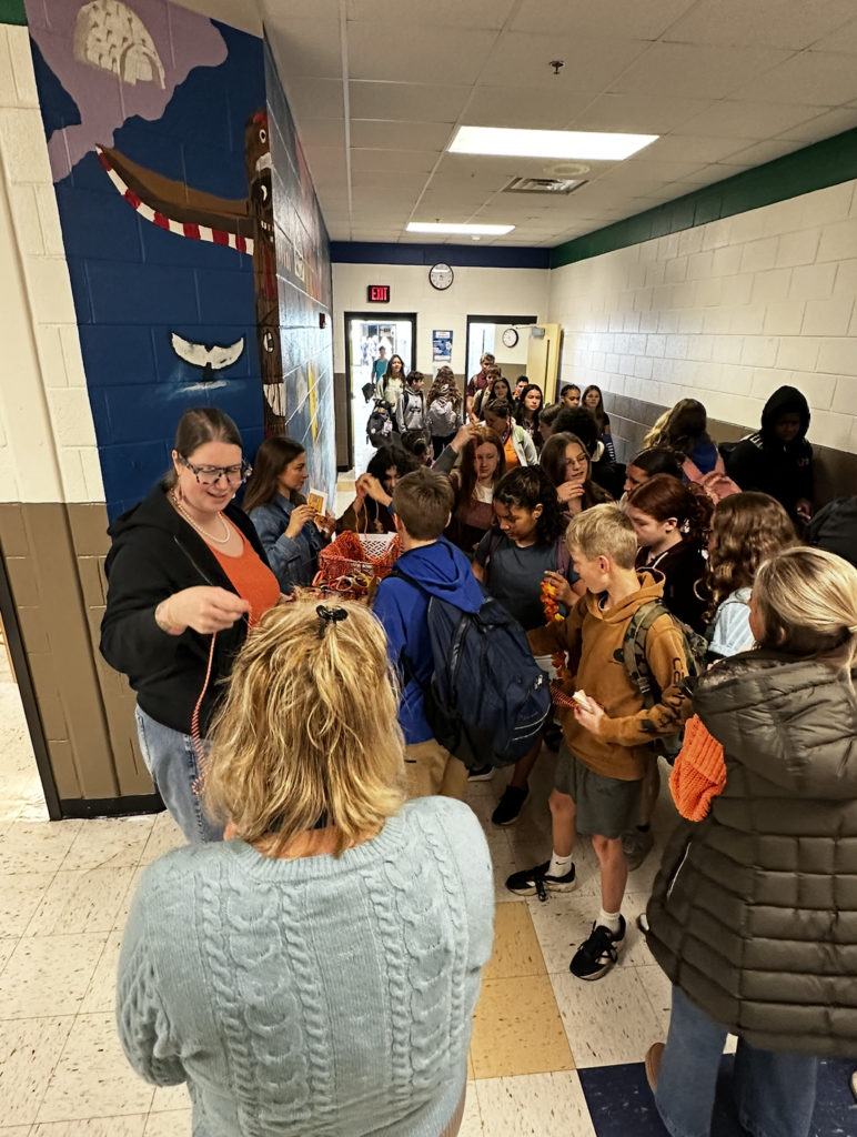 Teachers giving out orange necklaces and bracelets to students for Unity Day