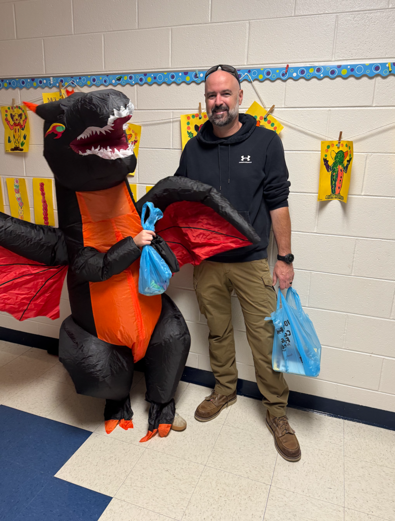 A student wearing an inflatable dinosaur costume and his dad.